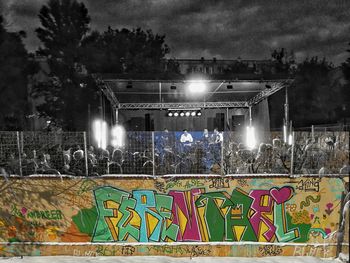 Graffiti on illuminated building against sky at night