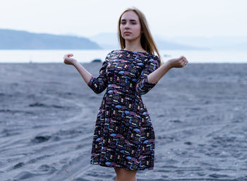 Portrait of young woman standing on sand at beach