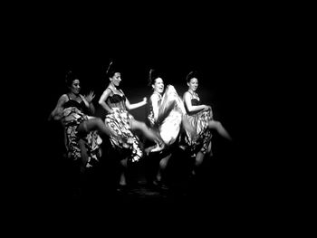 Group of people dancing against black background