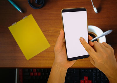 Low section of person holding smart phone on table