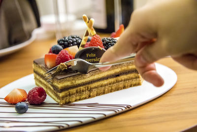 Close-up of man eating piece of chocolate cake food on table