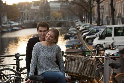 Young couple with bicycle by railing in city