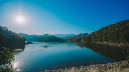 Scenic view of lake and mountains against blue sky