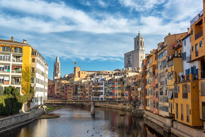 Bridge over canal amidst buildings in city against sky