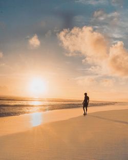Silhouette man standing at beach against sky during sunset