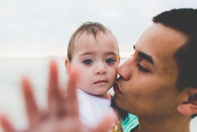 Close-up portrait of cute baby boy holding smart phone at home