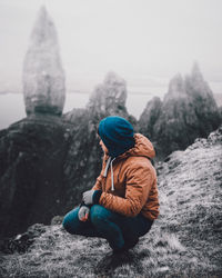 Rear view of man sitting on rock