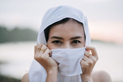 Portrait of woman covering face with scarf at beach