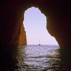 Silhouette rock formation in sea against sky