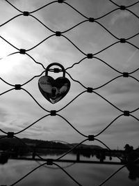 Close-up of chainlink fence against sky during sunset