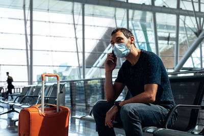 Young man wearing a face mask talking on the phone at the airport