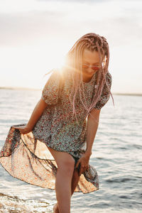 Woman standing at beach against sky