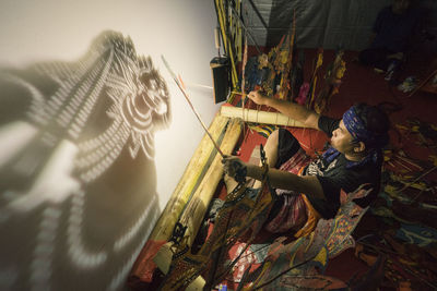 High angle view of man creating shadow on wall with puppets