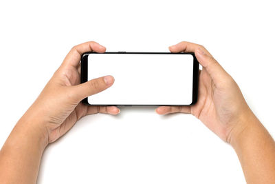 Cropped hands of woman using mobile phone against white background