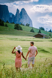 Rear view of couple on field against mountains