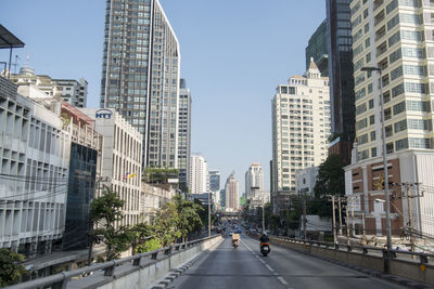 Road amidst buildings in city against sky