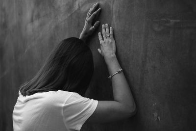 Side view of sad woman standing by wall