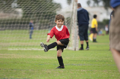 Young boy with big smile kicking an imaginary soccer ball