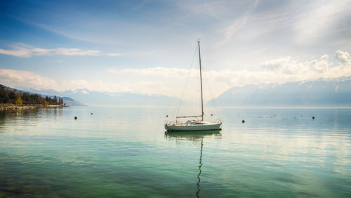 Sailboats moored on sea against sky