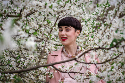 Portrait of a smiling young woman with pink flower