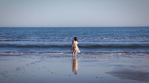 Full length of man standing on beach against clear sky