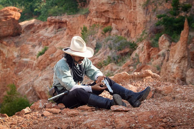 Rear view of man sitting on rock