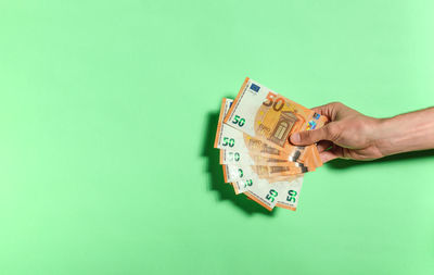 Close-up of hand holding paper against blue background