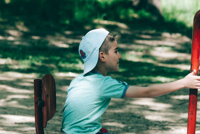 Side view of smiling boy playing on seesaw at playground