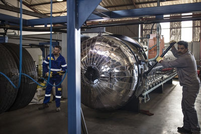 Tire repairmen working on machine in factory