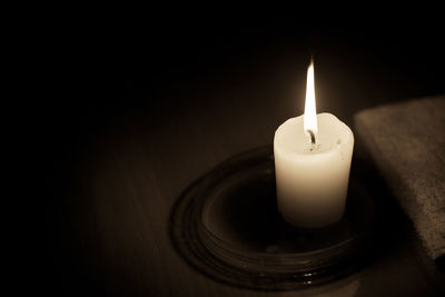 Close-up of lit candle in darkroom