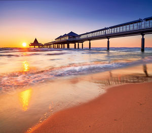 Bridge over sea against sky at sunset