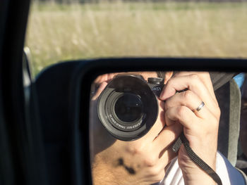 Midsection of woman photographing through car