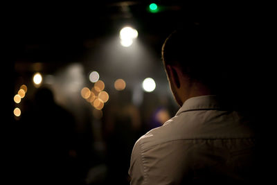 Rear view of a man against blurred lights