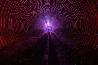 Silhouette of man in illuminated tunnel