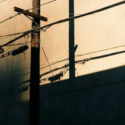 Low angle view of silhouette electricity pylon against sky