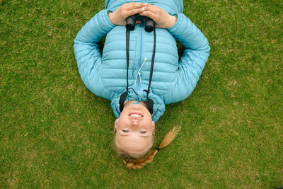 High angle portrait of smiling woman lying on grassy field