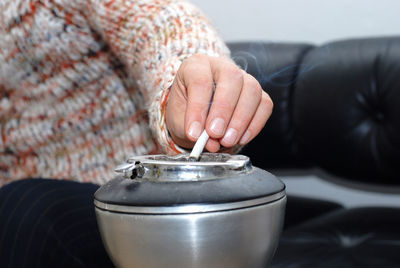 Cropped image of woman holding cigarette over ashtray