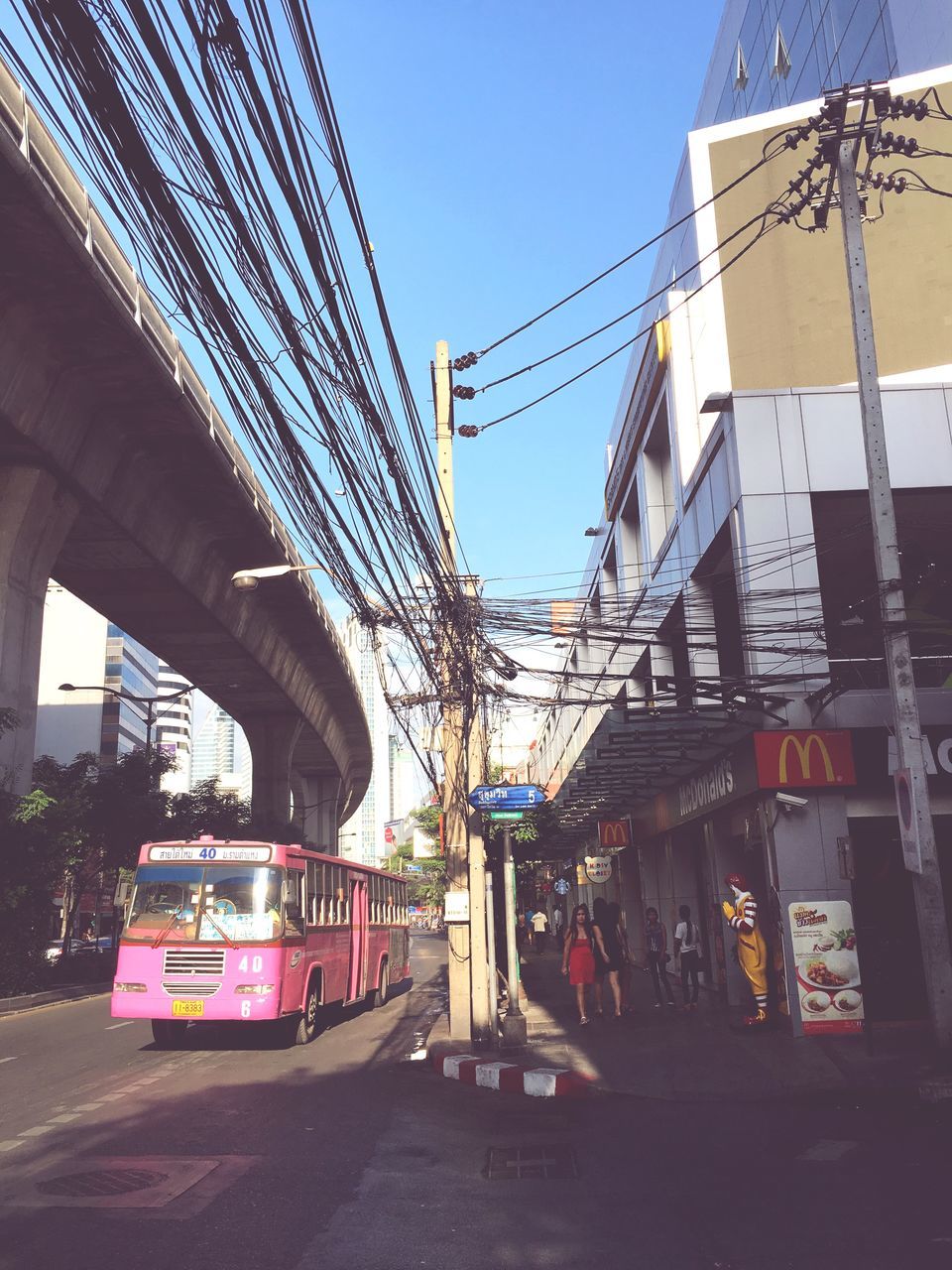 architecture, built structure, building exterior, transportation, city, clear sky, street, car, building, land vehicle, mode of transport, road, low angle view, residential building, day, sunlight, incidental people, outdoors, city life, sky