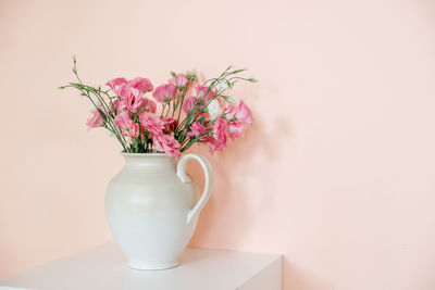 Flower vase on table against wall