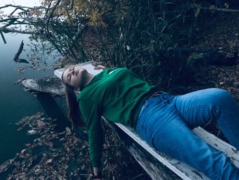 Young woman sleeping by lake on seat