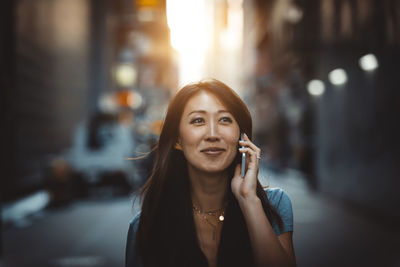 Portrait of smiling young woman using smart phone outdoors