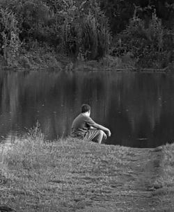 Rear view of man sitting in lake