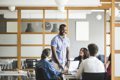 Smiling businessman discussing business plan with colleagues in meeting at board room