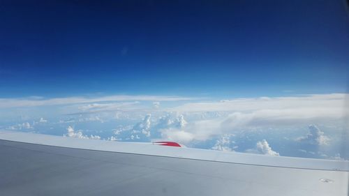 Airplane flying over landscape against blue sky