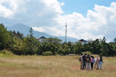 Rear view of people on field against sky