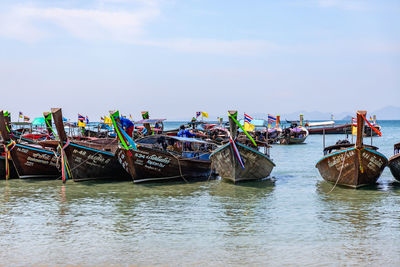 Fishing boats moored in river against sky