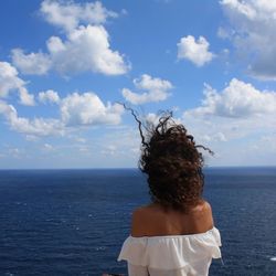 Rear view of man standing in sea against sky