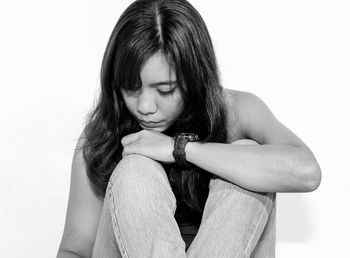 Thoughtful woman sitting against white background