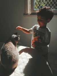 Cute boy playing with cat