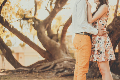 Midsection of couple embracing while standing in forest